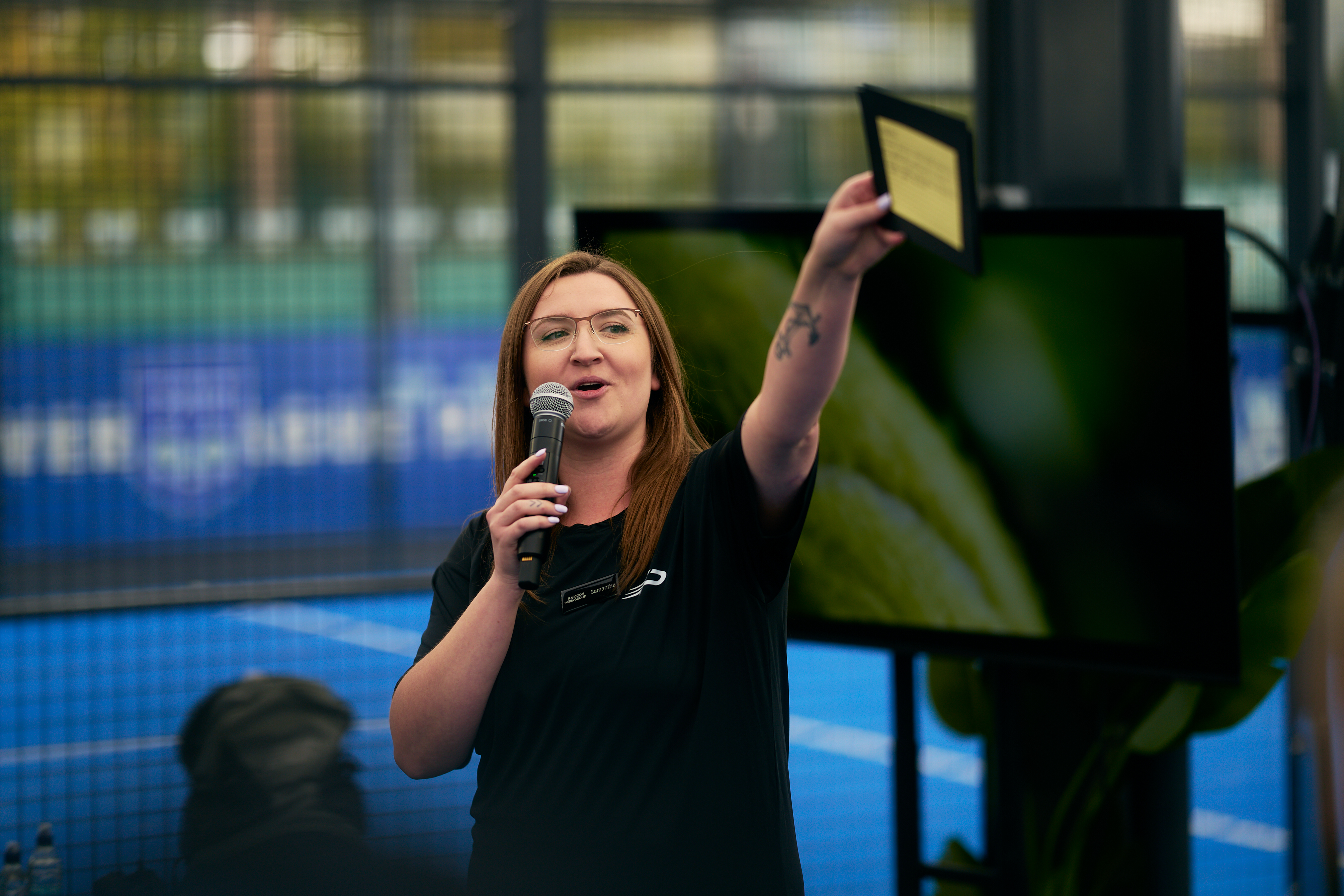 Host on the microphone holding up a prize