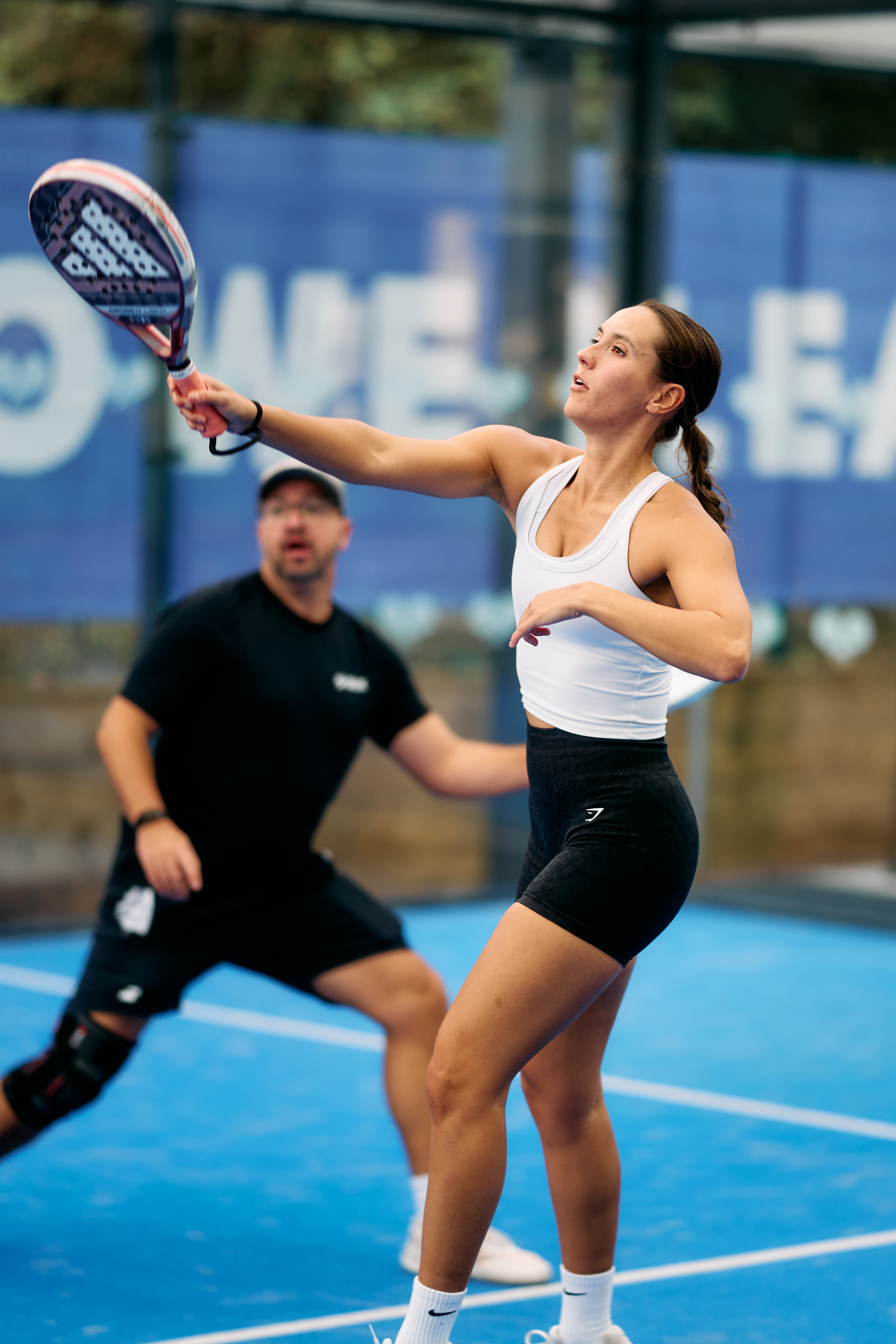 Player stretching for a high volley during a mixed doubles game