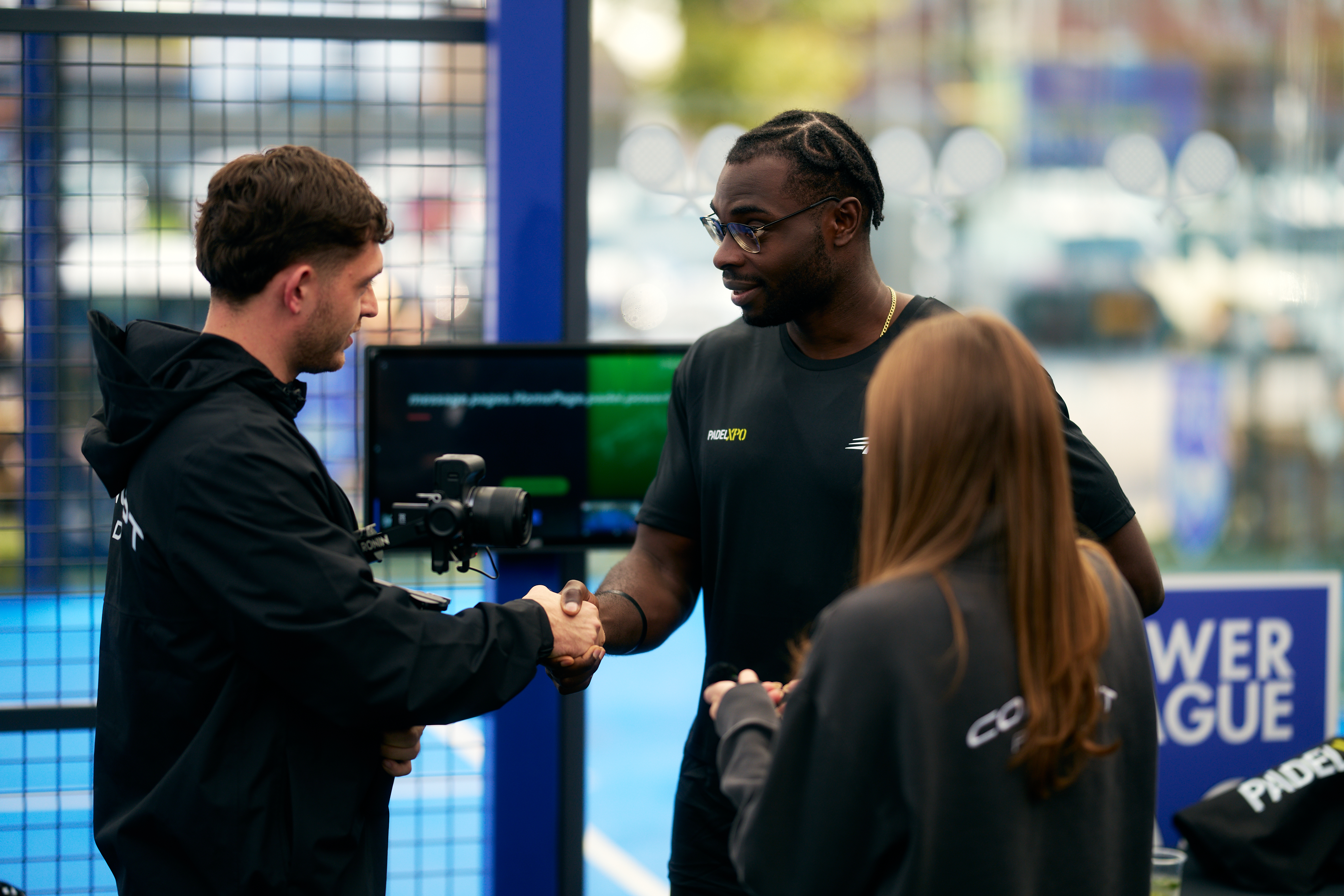 Guest shaking hands with a videographer beside the court