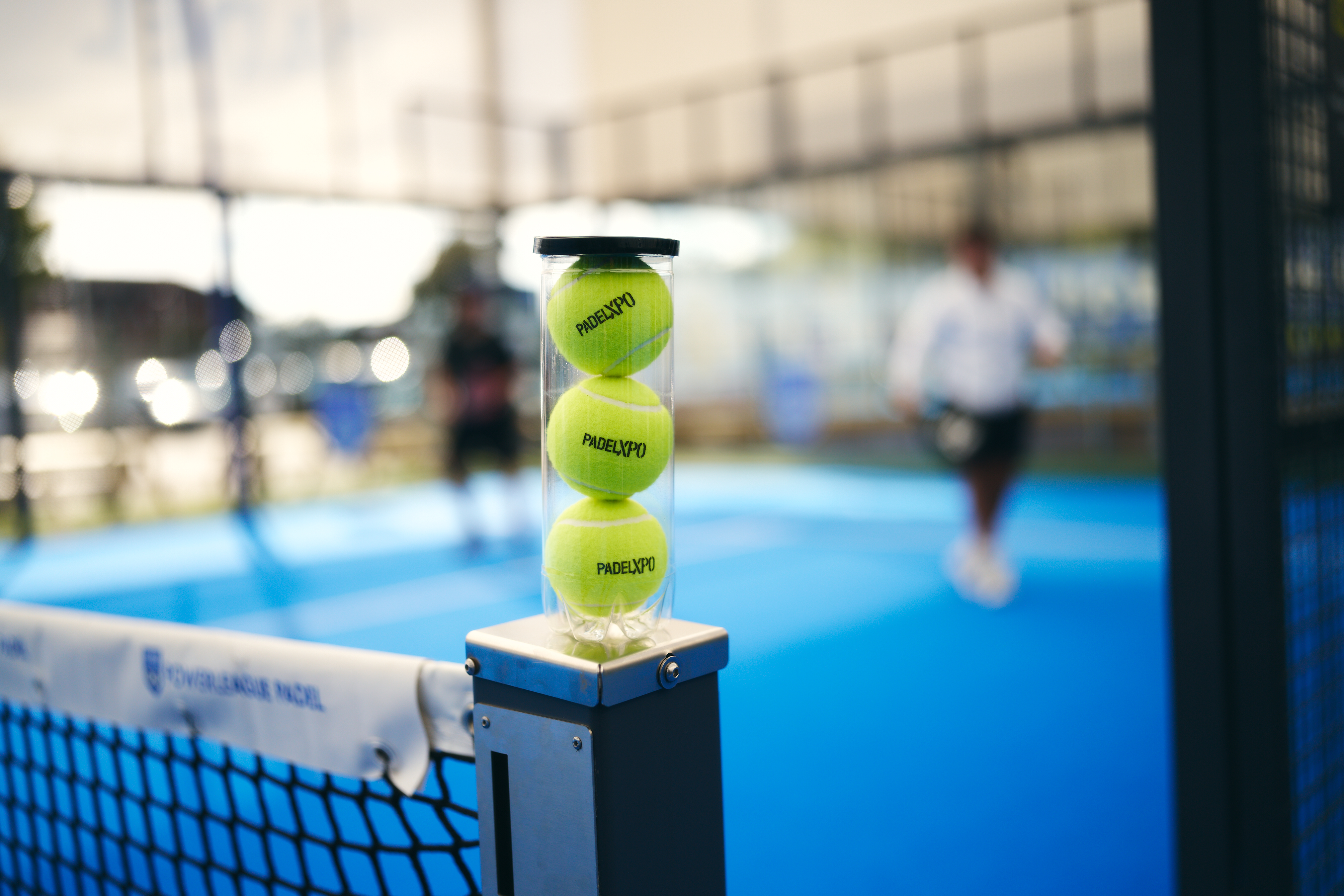 Tube of PadelXPO branded balls on the net post