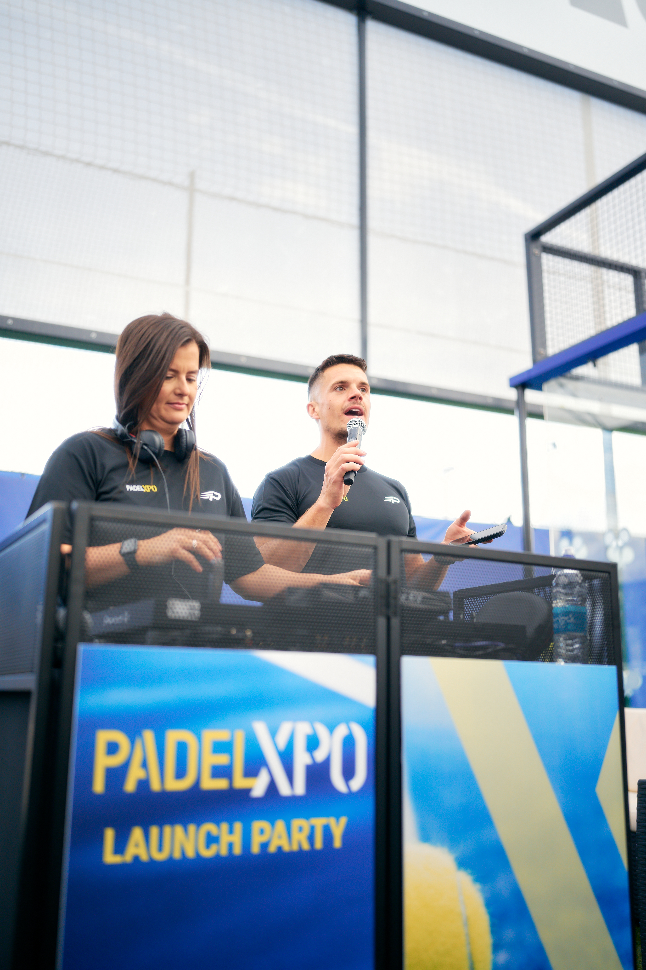 Two hosts on the microphone at the PadelXPO Launch Party booth