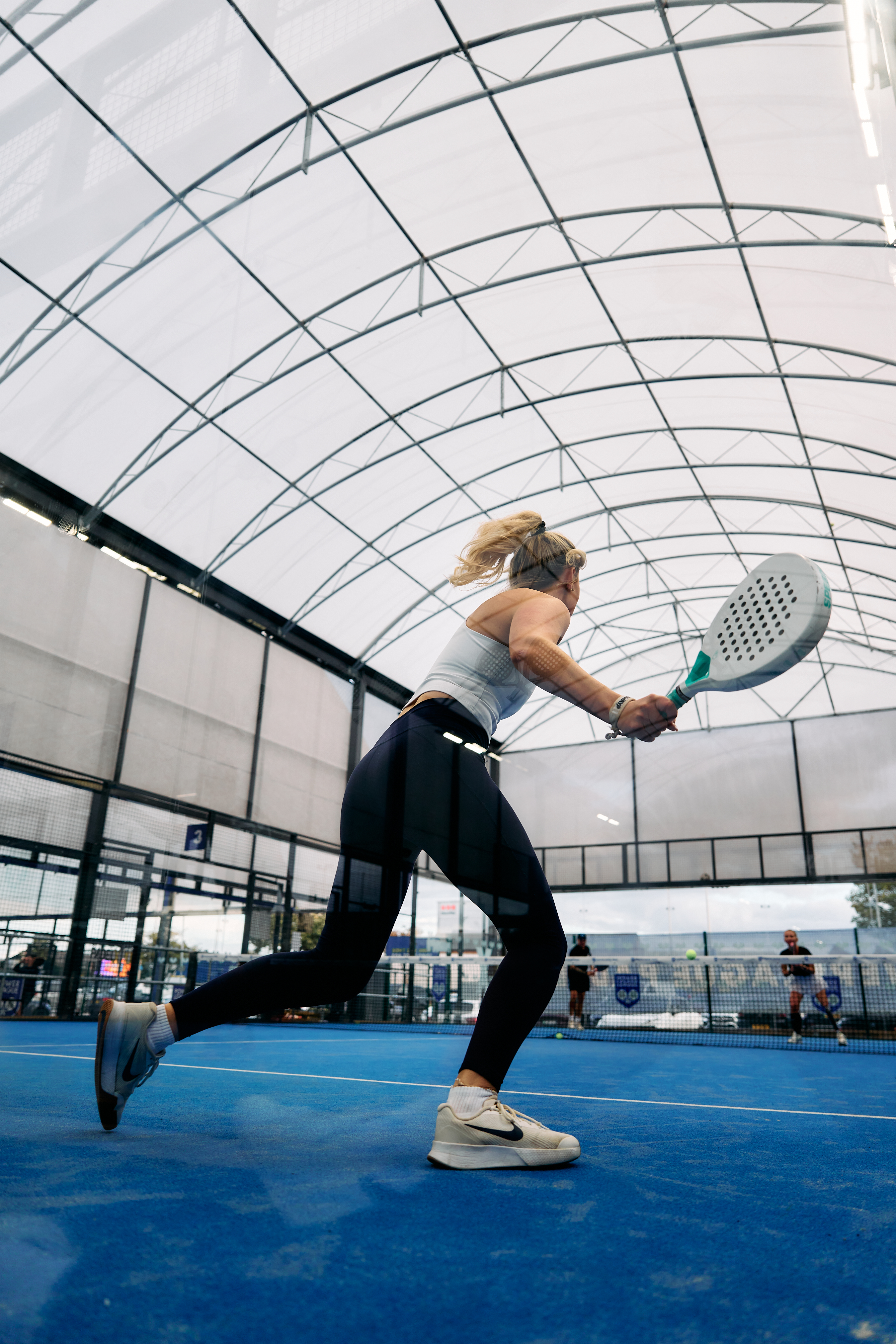 Player hitting a backhand under the covered court roof
